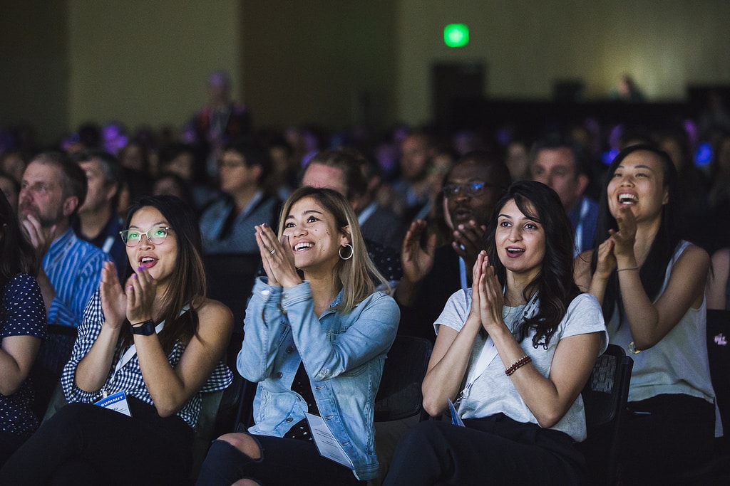 A group of people in the audience at Summit 2019 applauding