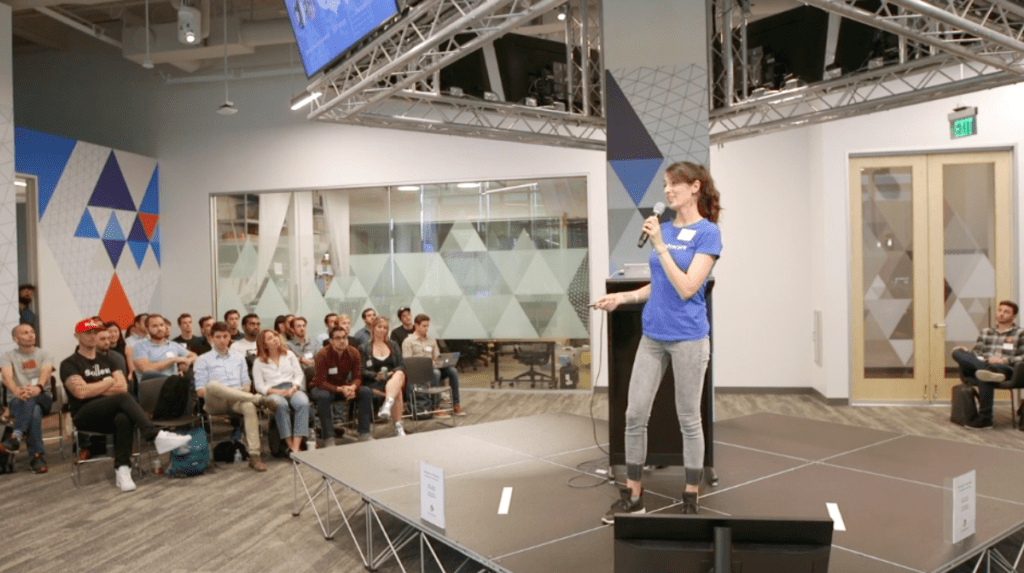 Mariel Reed presents to a crowd wearing a blue tshirt and grey jeans