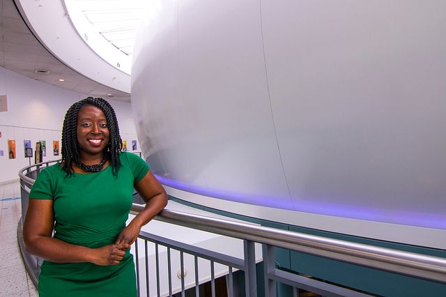 Afua Bruce wears a green dress and leans against a metal railing