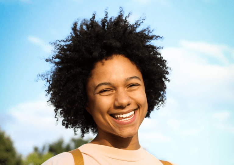 Ryn Adkins smiles against a blue background.
