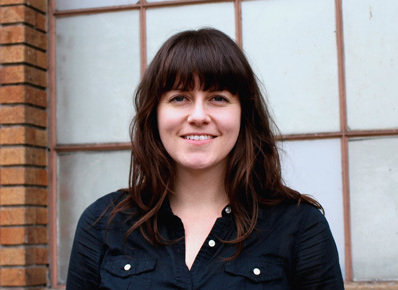 Julie Sutherland smiles at the camera in front of a window.