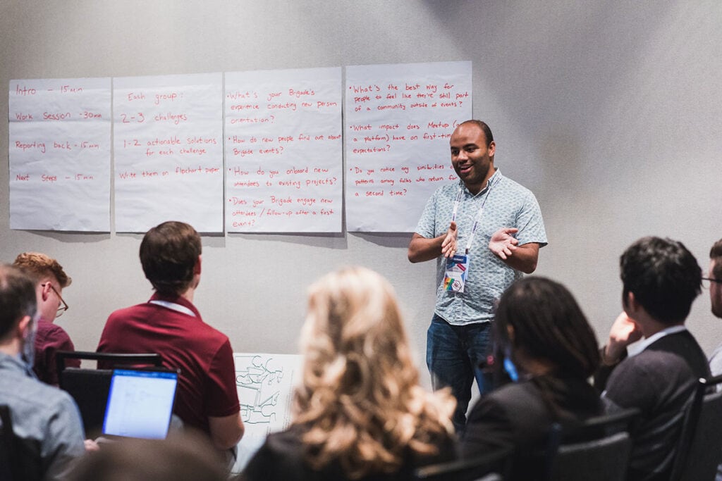 Person enthusiastically presenting in front of a group of seated people